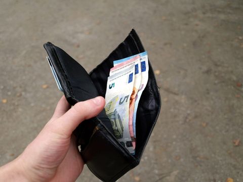 Hand hält ein geöffnetes schwarzes Portemonnaie mit mehreren Euro-Banknoten