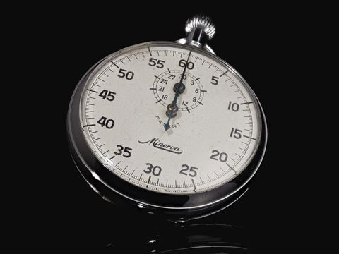 Analoge Stoppuhr mit weißem Zifferblatt und Sekundenskala vor schwarzem Hintergrund