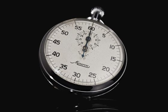 Analoge Stoppuhr mit weißem Zifferblatt und Sekundenskala vor schwarzem Hintergrund